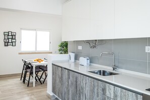 A modern kitchen with a central island, a built-in sink, and a dining area with chairs and a table.