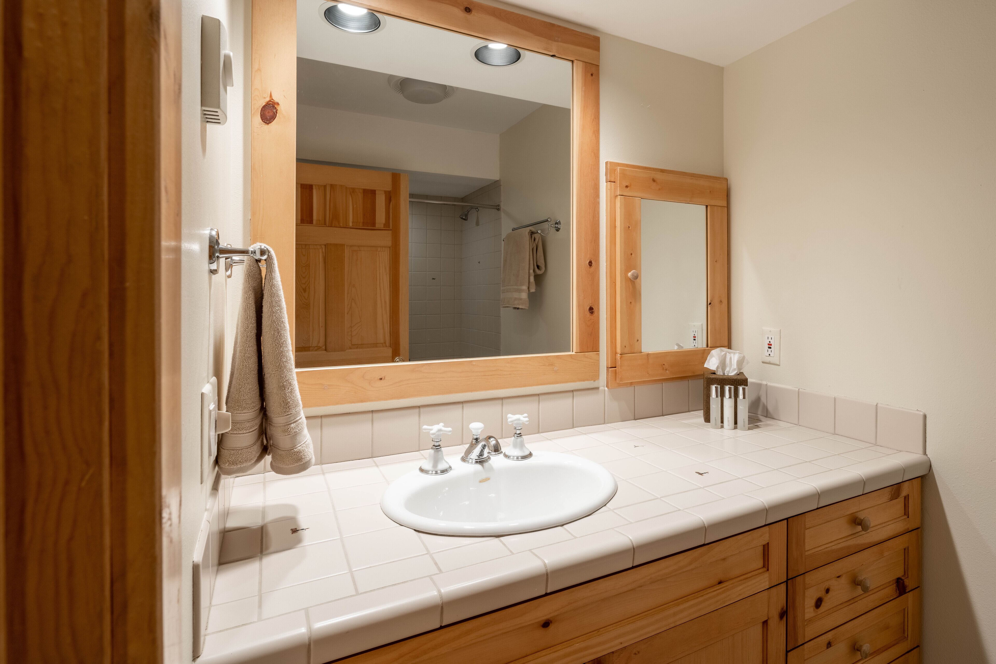 A bathroom with a white sink, wooden cabinets, and a large mirror.