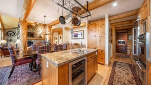 Une cuisine spacieuse dotée de meubles en bois, de plans de travail en granit et d’un porte-casseroles suspendu.