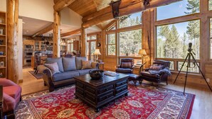 L’intérieur d’une cabane en rondins présente un espace de vie avec un canapé, une table basse et un tapis rouge à motifs.