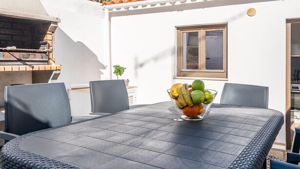 A patio with a table, chairs, and a bowl of fruit.