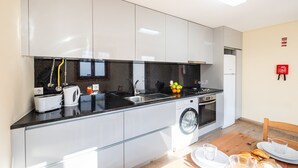 A modern kitchen with white cabinets, a black countertop, a washing machine, and a dining area with a table set for breakfast.