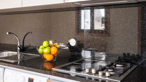 A kitchen with a stainless steel range, a bowl of fruit, and a window reflecting the outside.