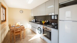 A compact kitchen with a washing machine, a stove, and a refrigerator.