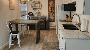 Een moderne keuken met een eetgedeelte, met een kroonluchter, een groot kunstwerk van veren en een ingebouwde magnetron.