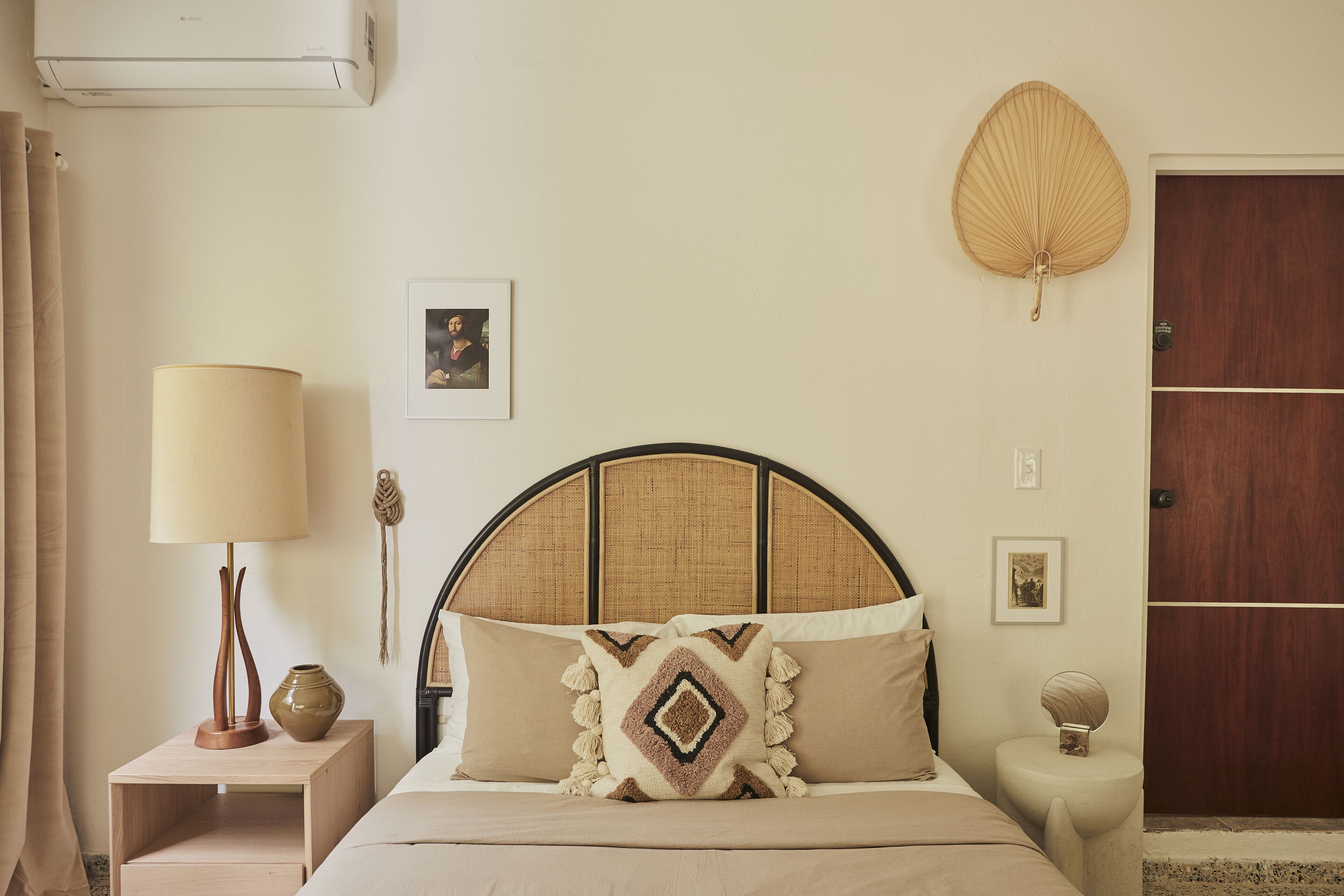 A neatly arranged bedroom with a bed, bedside table, lamp, and a wall-mounted decorative item.