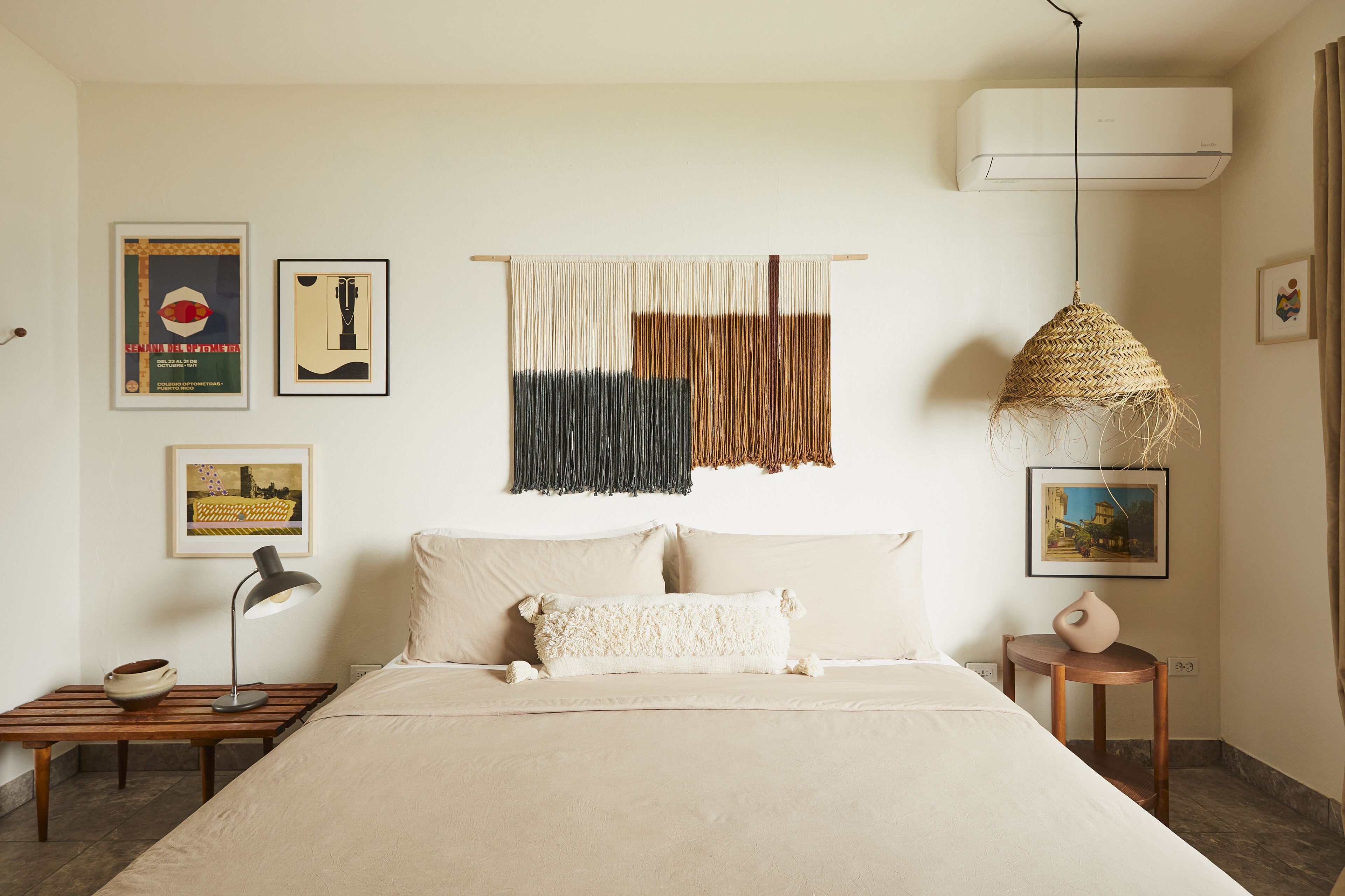 Une chambre à coucher avec un lit, une table de chevet, une lampe et des œuvres d’art murales.
