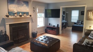 Una sala de estar con chimenea, televisor y piano.