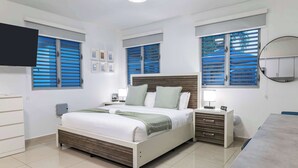 Une chambre à coucher moderne, avec un lit, des tables de chevet, un bureau et un téléviseur.
