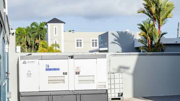 Een dak met elektrische apparatuur, een gebouw met een toren en palmbomen.