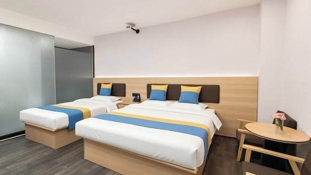 A hotel room with two beds, a small table, and a chair.
