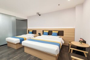 Una habitación de hotel con dos camas, una mesita y una silla.