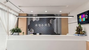 A reception desk with a modern design, a digital screen, and a decorative plant.