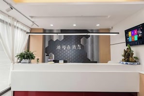 A reception desk with a modern design, a digital screen, and a decorative plant.