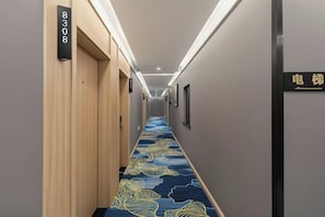 Un pasillo de hotel con alfombra azul, puertas de madera y un cartel que indica el número de habitación 8308.