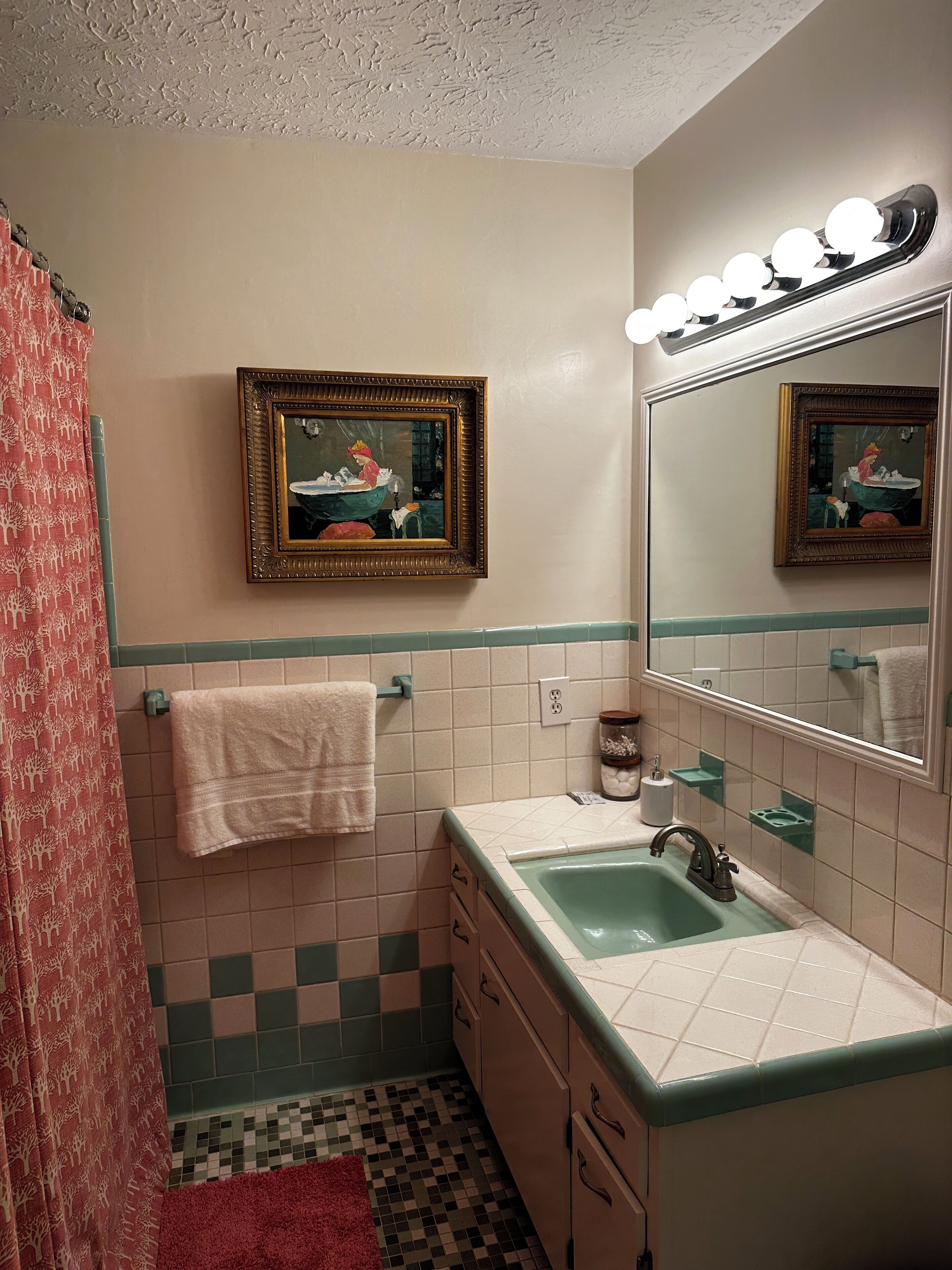 A bathroom with a sink, mirror, and two framed pictures on the wall.