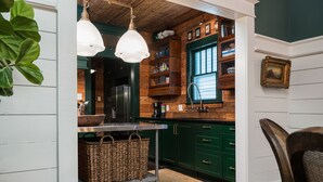 Una cocina con armarios de madera, un refrigerador de acero inoxidable y lámparas colgantes.