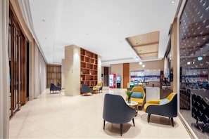 A modern hotel lobby with seating areas, a reception desk, and a large wooden bookshelf. - Yeste Hotel (Yulin Yudong New District Wentilu) (Yulin)