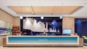 Vastaanottotiski, jonka taustalla näkyy kaupunkimaisema, vastaanottovirkailija ja digitaalinen näyttö.