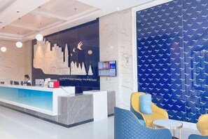 A reception area with a counter, seating, and a wall with a pattern. - Yeste Hotel (Yulin Yudong New District Wentilu) (Yulin)