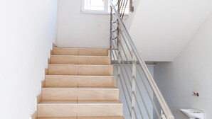 A staircase with wooden steps and a metal railing, leading to a landing with a window and a sink. - Apartment Josip - One Bedroom apartment (Zagreb)