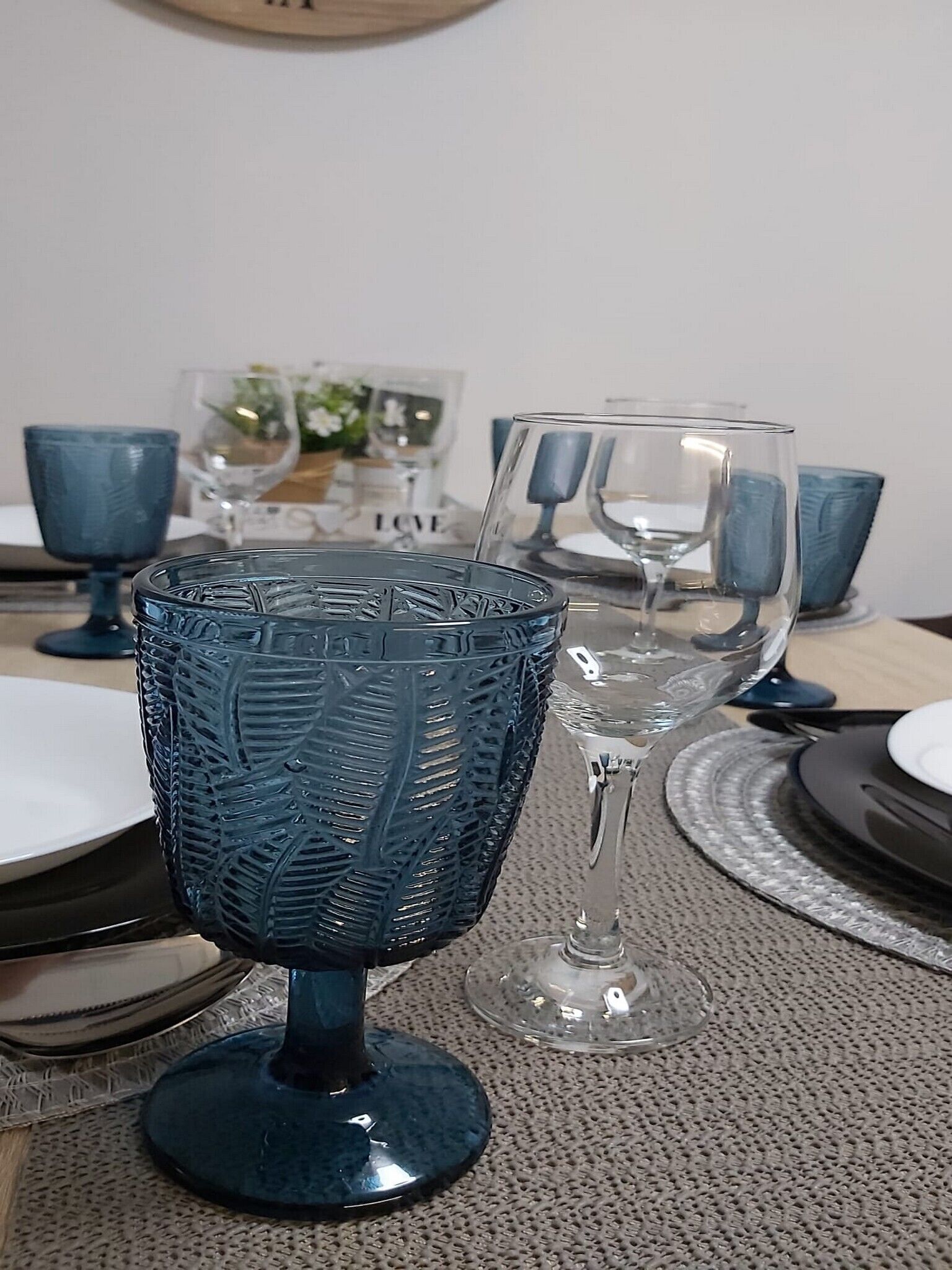 A dining table with blue glassware and clear glassware.