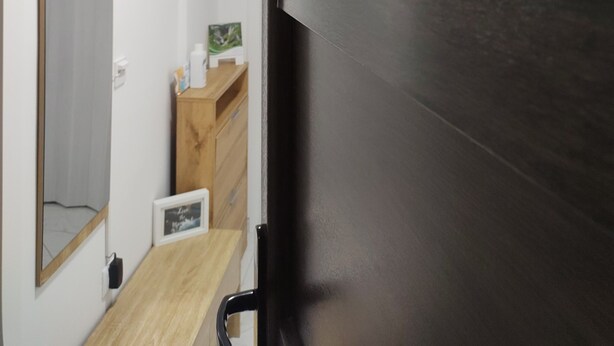 Une cuisine moderne avec un réfrigérateur de couleur sombre, des armoires en bois et un petit plan de travail.