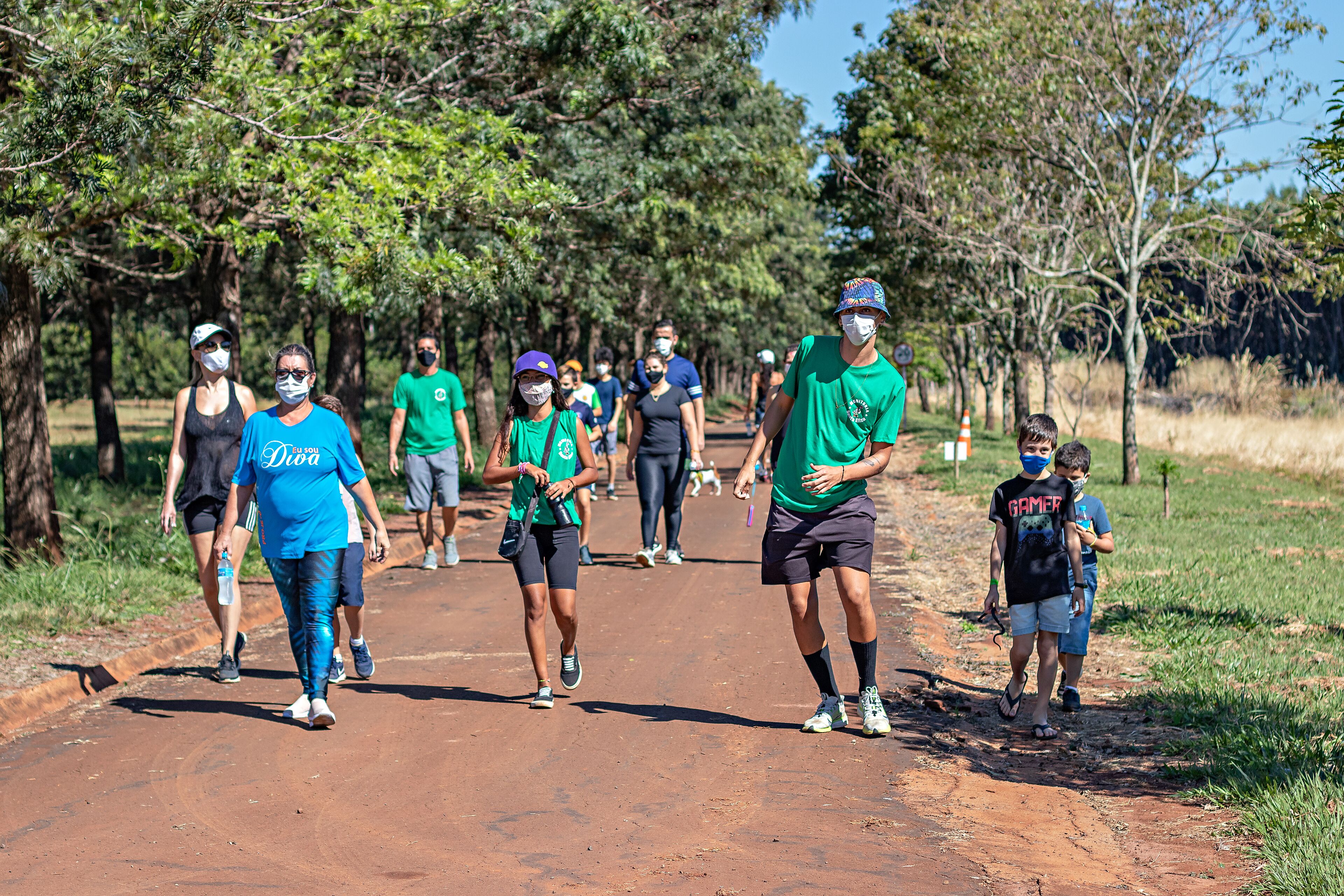 A group of people walking on a dirt path surrounded by trees.