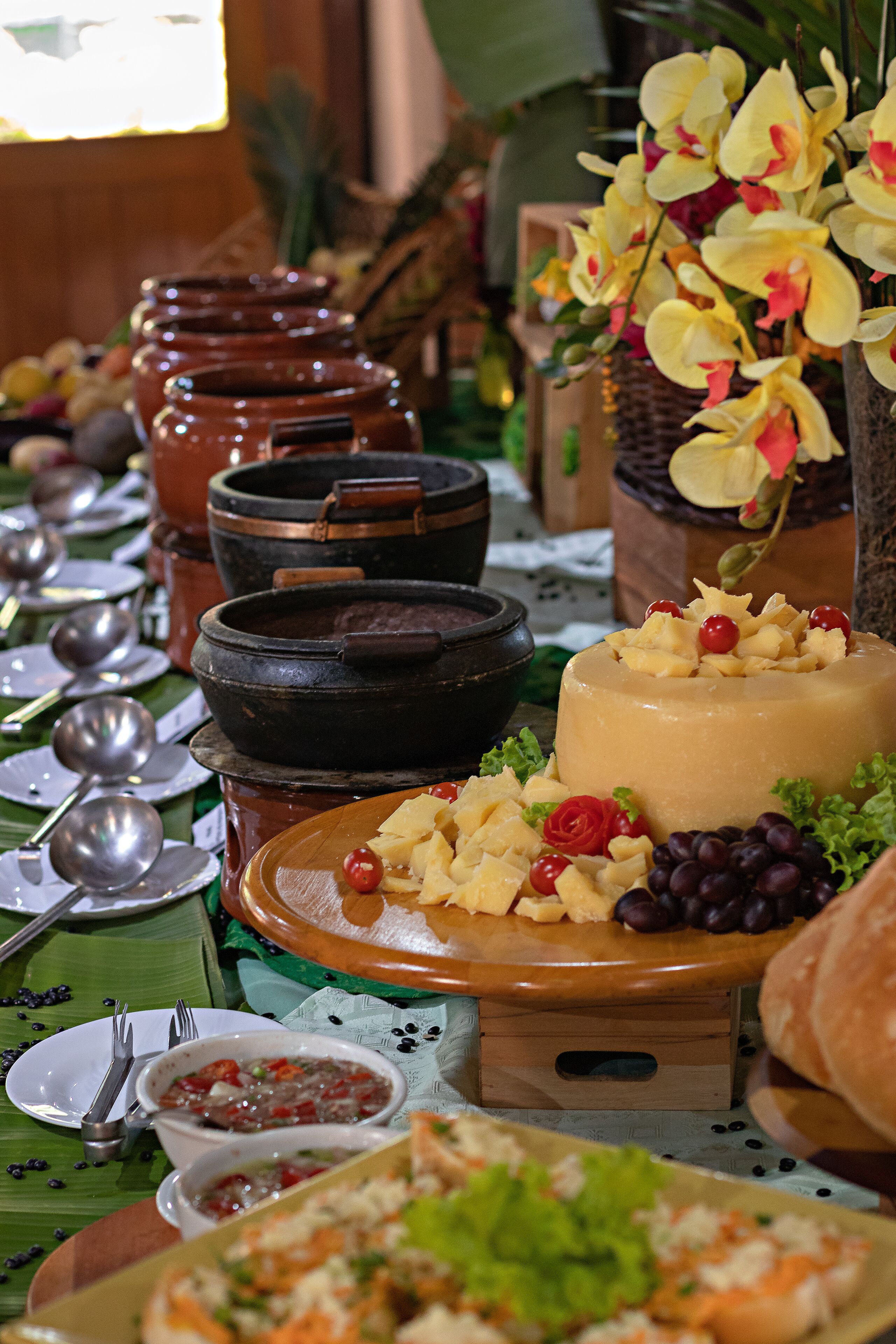A table with various dishes, including a cake with fruit and grapes, surrounded by bowls and plates.