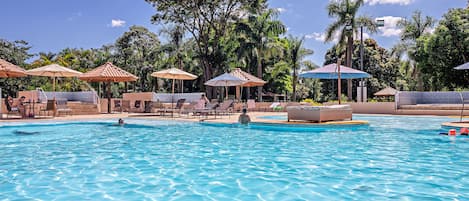 Una piscina al aire libre, sombrillas, sillones reclinables de piscina