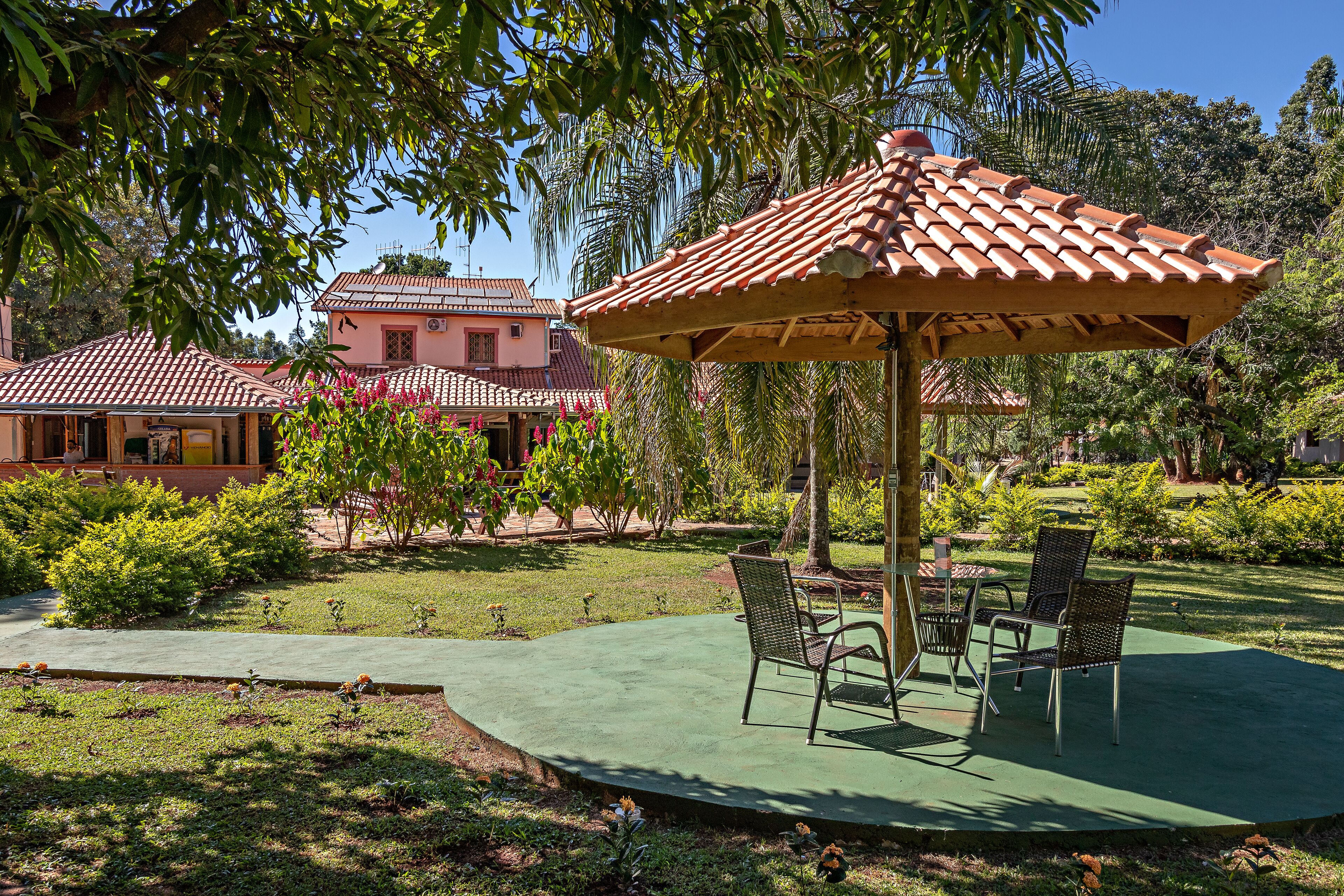 Un patio con una pérgola, dos sillas y una mesa.
