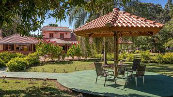 Un patio con una pérgola, dos sillas y una mesa.
