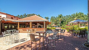 Un patio al aire libre con suelo de ladrillo, muebles de mimbre y sombrillas que dan sombra.