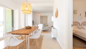 Un espacio habitable amplio y luminoso con una mesa de comedor de madera, sillas blancas, un sofá y una cama.