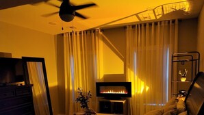 A bedroom with a bed, a ceiling fan, a fireplace, and a TV. - New Modern Home (Joplin)