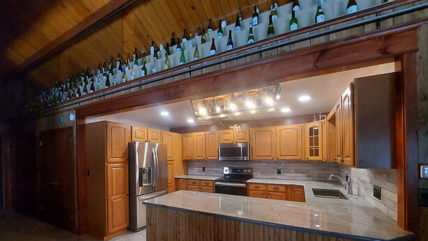 Une cuisine moderne avec des meubles en bois, des appareils en acier inoxydable et un plan de travail en marbre.