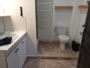 Un baño pequeño con un lavamanos blanco, un inodoro y una puerta de ducha.