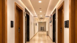 Un pasillo de hotel con puertas de madera, letreros de habitaciones numeradas y un piso de baldosas impecable.