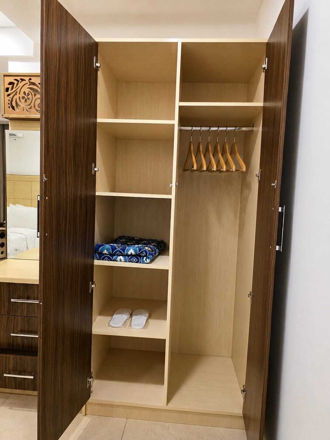 Un vestidor amplio con varias estanterías, una barra para colgar ropa y un par de zapatillas en la repisa inferior.