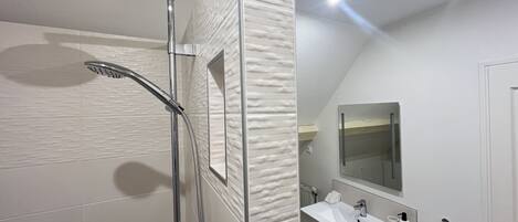 Ein modernes Badezimmer mit Dusche, Waschbecken und Spiegel.