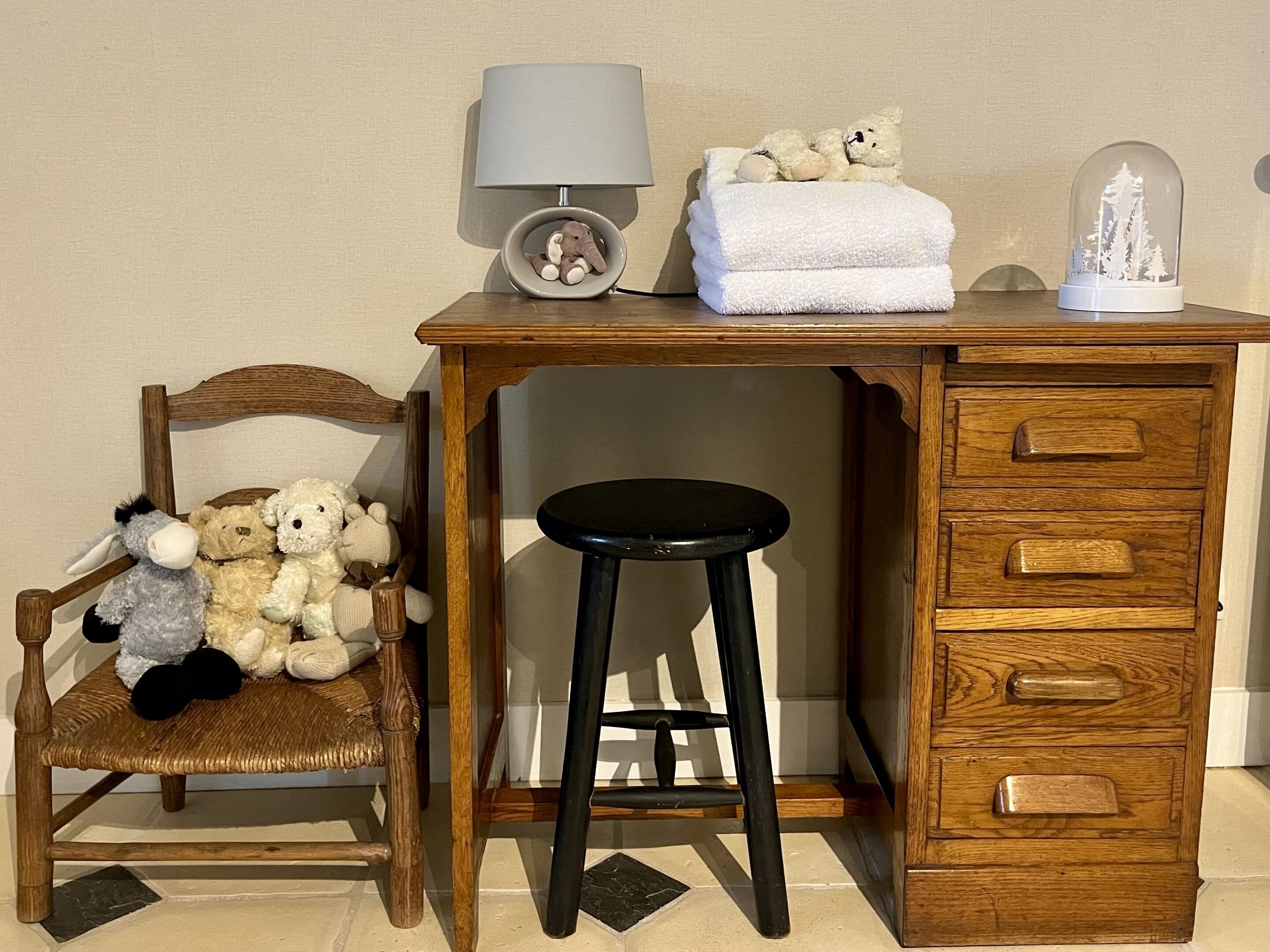 Un bureau en bois, une lampe, une chaise et un ours en peluche.