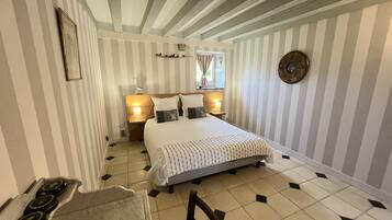 Een hotelkamer met een bed, twee nachtkastjes met lampen, een houten hoofdeinde, een ronde wanddecoratie en een betegelde vloer.