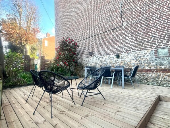 An outdoor patio with a brick wall, a small table, and black chairs. - Family home, townhouse in d'Etretat (Étretat)