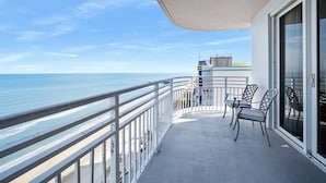 Een balkon met uitzicht op zee, twee stoelen en een glazen deur.
