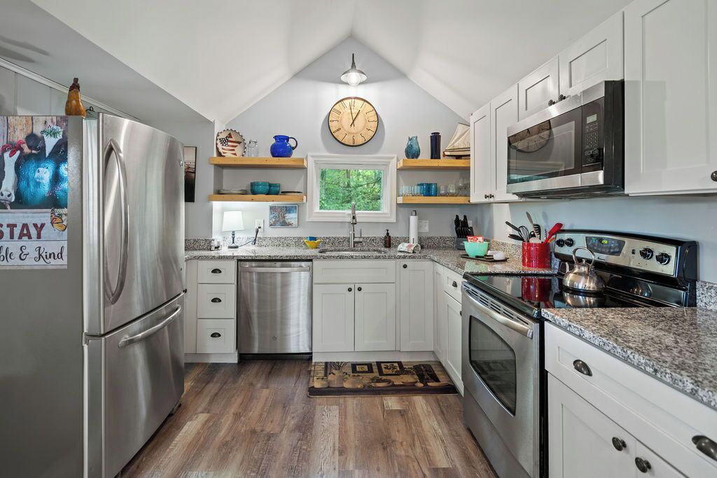 A modern kitchen with stainless steel appliances, white cabinets, and a wooden floor.