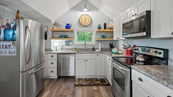 A modern kitchen with stainless steel appliances, white cabinets, and a wooden floor.