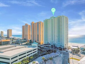 A high-rise hotel with multiple floors, a parking garage, and a beach view.