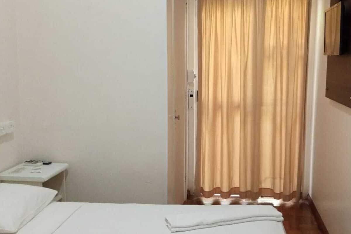Ein Hotelzimmer mit Bett, Nachttisch, Spiegel und Vorhang.