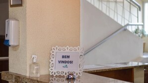 Una recepción con un letrero que dice "BEM VINDOS!" y un dispensador de gel antibacterial.