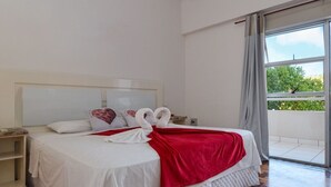 Una habitación de hotel con una cama grande, una manta roja y dos almohadas blancas con forma de cisne.